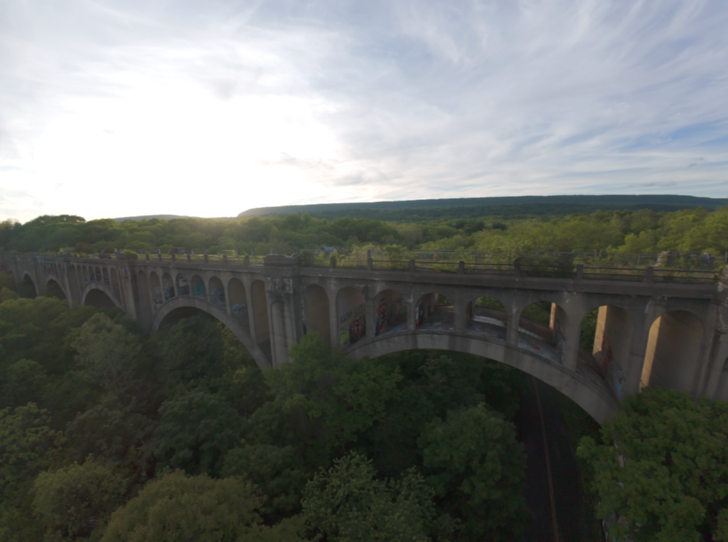 Aerial drone view of a stone arch bridge over a wooded valley